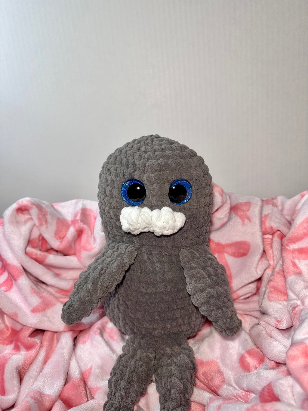 Handmade crochet gray seal plushie with blue sparkle eyes and white mustache